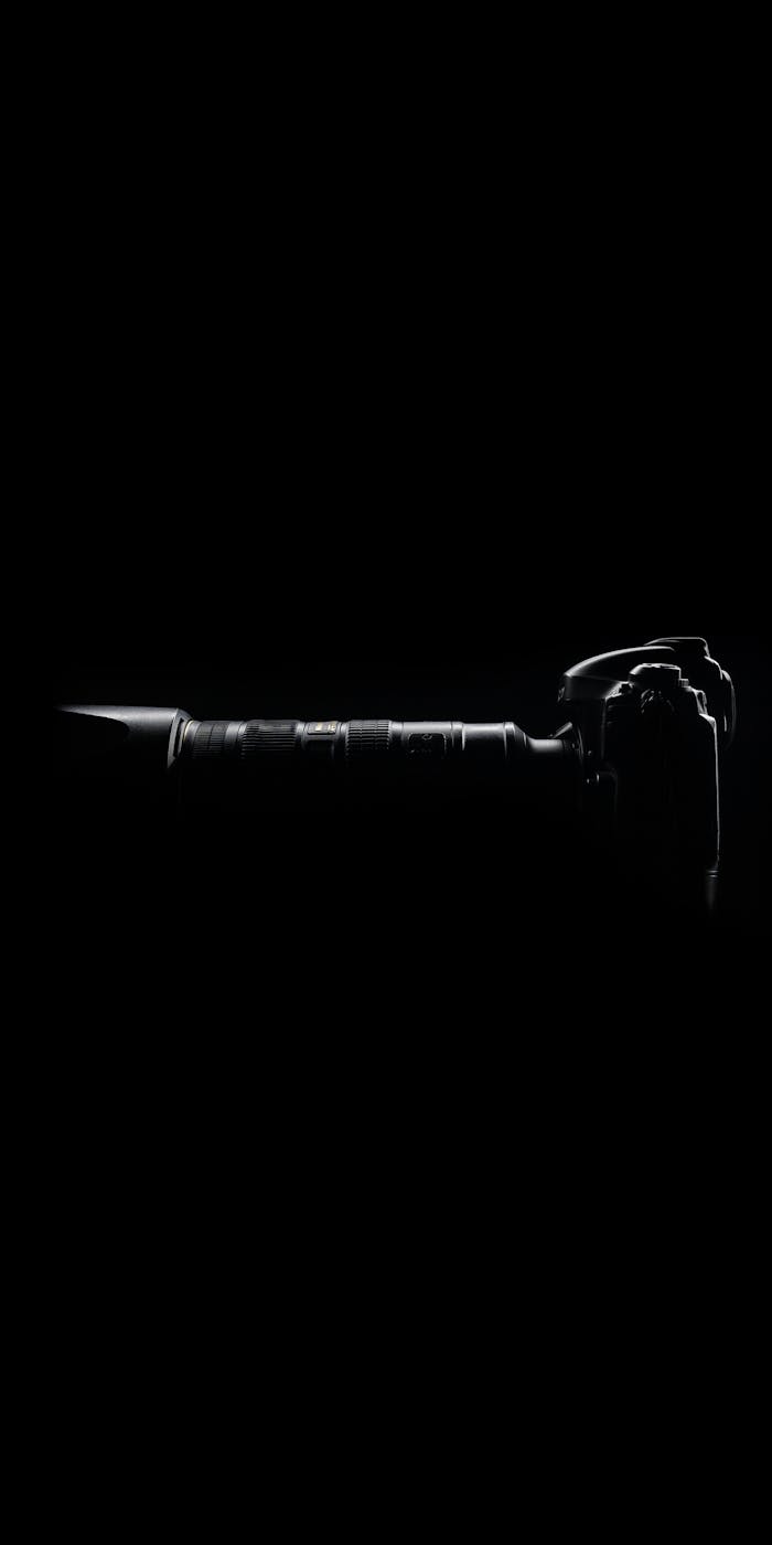 Veille & Innovation Silhouette of a modern camera with lens against a dark black backdrop.
