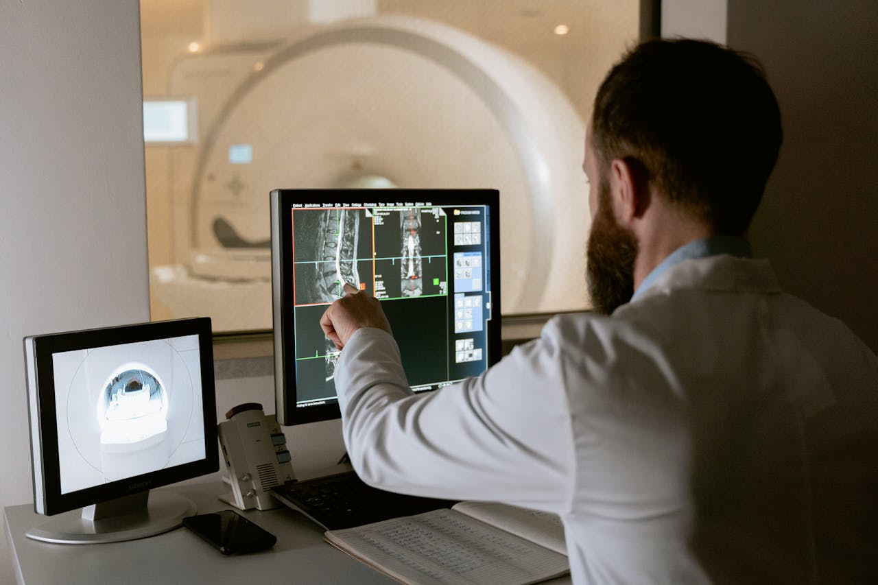 Principes Medical professional reviewing MRI scans on computer screens for diagnostic purposes.