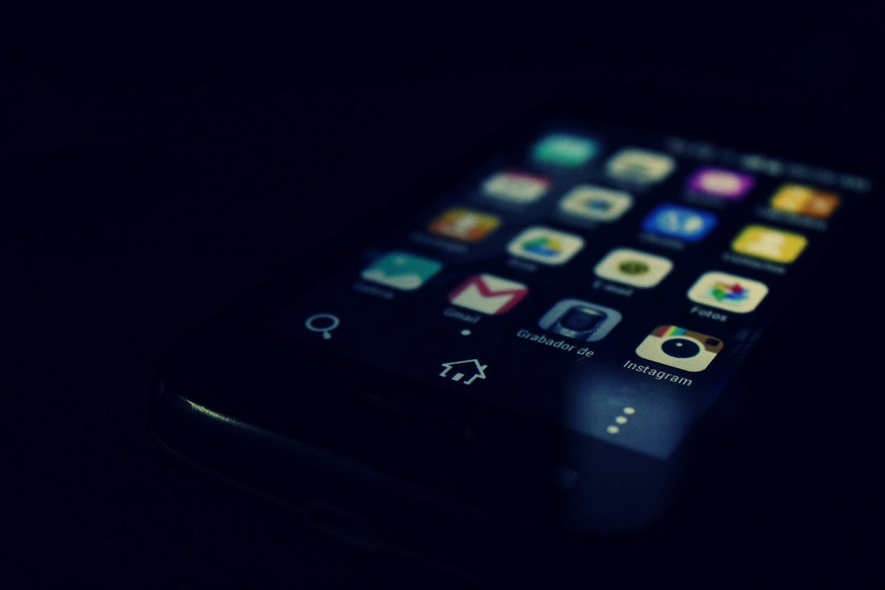 Principes Dark-themed close-up of a smartphone screen highlighting various apps and touchscreen technology.